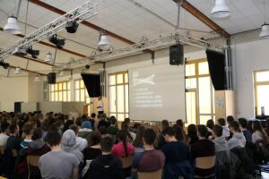 Schüler sitzen in einem Raum und schauen auf eine Leinwand.