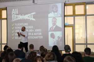 Ein Referent spricht vor Studierenden über seine Lebensgeschichte.