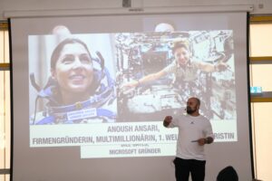 Mann spricht vor einer Präsentation über Anoush Ansari und Raumfahrt.