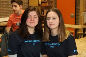Zwei Schülerinnen in T-Shirts mit dem Aufdruck "NUTELLANAUTEN" in einer Schulküche.