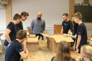 Schülerinnen und Schüler arbeiten an einem Projekt mit Kartons in einem Klassenraum.