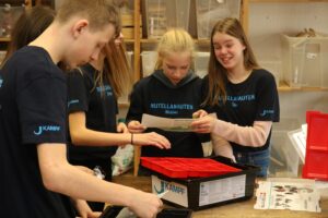 Schülerinnen und Schüler arbeiten gemeinsam am Tisch mit Materialien.