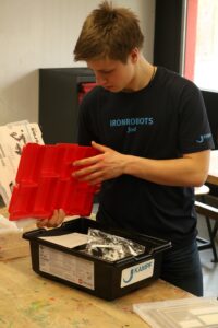 Ein Jugendlicher kontrolliert Materialien in einem schwarzen Behälter.