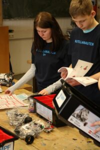 Schüler arbeiten an einem Roboterbauprojekt mit Anleitungen und Komponenten.