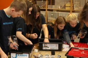 Schülerinnen und Schüler arbeiten am Tisch mit verschiedenen Materialien und Werkzeugen.