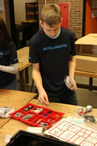 Ein Schüler sortiert Bauteile in einem Workshop.