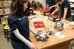 Schüler arbeiten an Robotern und Technikprojekten in einem Klassenraum.
