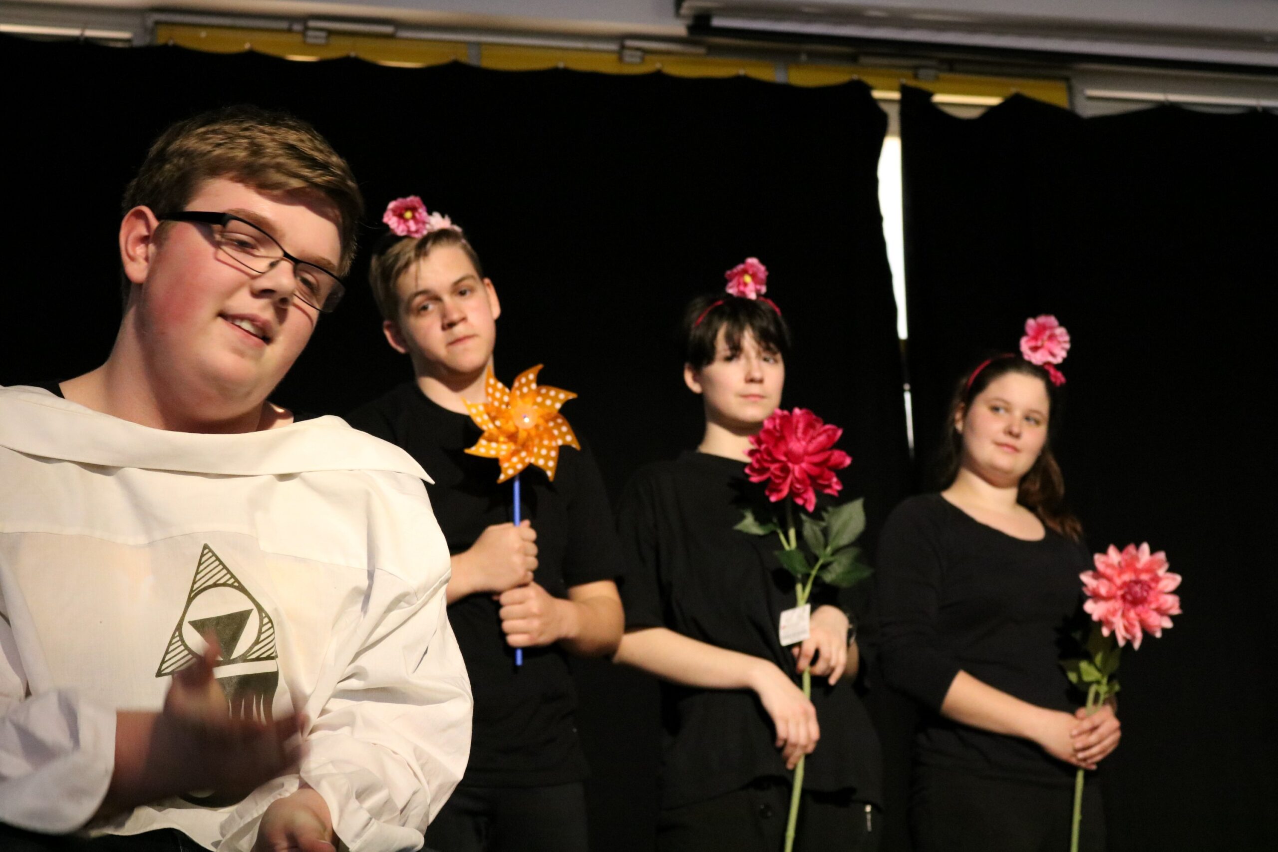 Schülerinnen und Schüler führen ein Theaterstück mit Blumen und Kostümen auf.