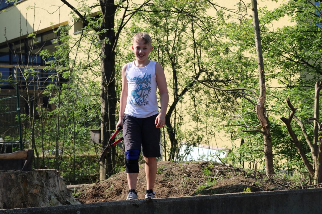 Ein Junge steht auf einer Mauer in einem Garten.