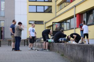 Gruppe von Personen arbeitet an einem Projekt im Freien vor einem Gebäude.