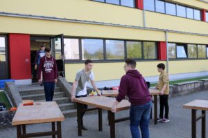 Schüler tragen Tische aus einem Schulgebäude nach draußen.