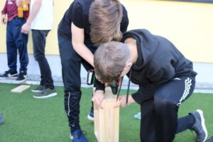 Zwei Schüler arbeiten zusammen an einem Holzprojekt im Freien.