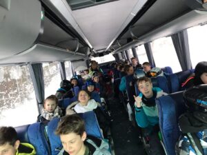 Schüler sitzen im Bus und lächeln, während es draußen schneit.