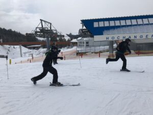 Zwei Skifahrer fahren auf einer Schneepiste in einem Skigebiet.