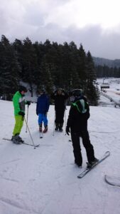Gruppe von vier Skifahrern in Winterkleidung auf einer Piste im Schnee.