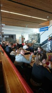 Schülerinnen und Schüler sitzen zusammen an einem Tisch in einer Cafeteria.