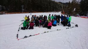 Gruppe von etwa 40 Personen posiert im Schnee auf einer Piste.
