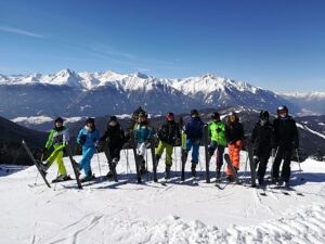 Gruppe von Skifahrern in bunten Skianzügen auf einem schneebedeckten Berg.