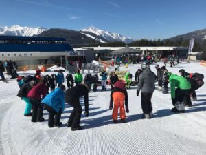 Gruppe von Skifahrern auf einer Schneewiese beim Dehnen vor dem Skifahren.
