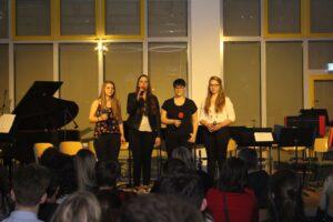 Schülerinnen stehen auf der Bühne und singen vor Publikum.