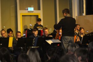 Schüler spielen in einer Band, während ein Dirigent sie leitet.