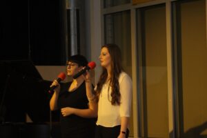 Zwei Sängerinnen stehen auf der Bühne und singen ins Mikrofon.