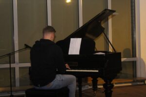 Ein junger Mann spielt an einem schwarzen Klavier.