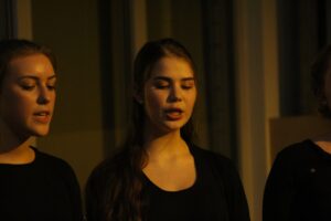 Drei Frauen singen gemeinsam, zwei davon mit geschlossenen Augen.
