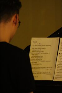 Ein Junge spielt Klavier und liest von einem Notenblatt.