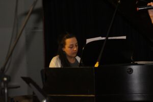 Schülerin spielt Klavier auf einer Bühne während einer Aufführung.