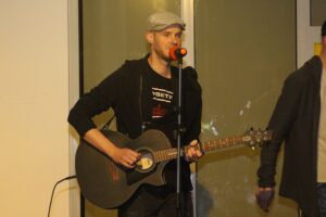 Ein Mann spielt Gitarre und singt in ein Mikrofon.