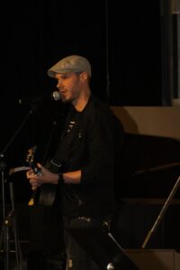 Ein Musiker steht auf der Bühne und spielt Gitarre.