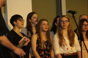 Schülerinnen stehen gemeinsam auf der Bühne und singen.