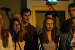 Schülerinnen und Schüler singen auf einer Bühne beim Auftritt.