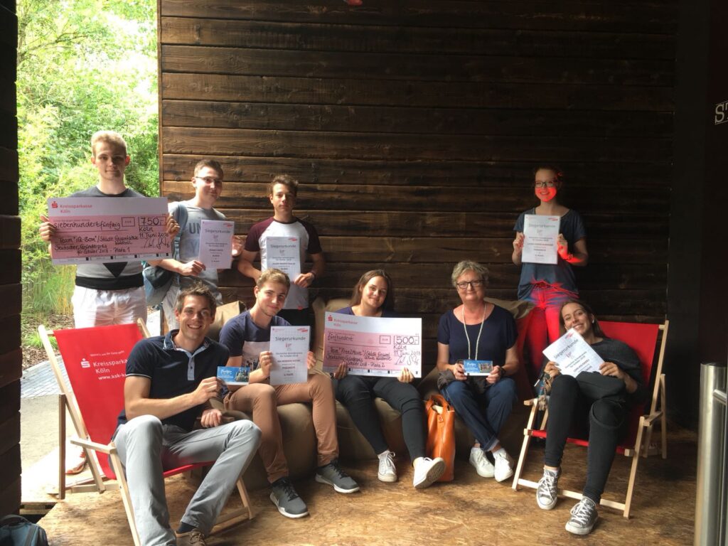 Gruppensitzung mit neun Personen, die Plakate in der Hand halten und lächeln.
