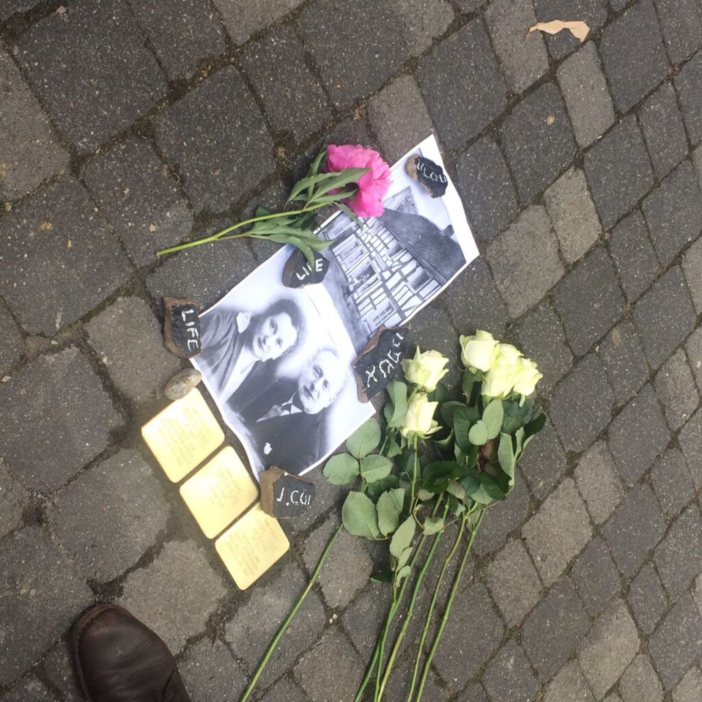 Blumen und Fotos liegen auf dem Boden, umgeben von zwei Holzstücken.