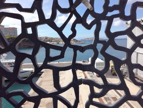Blick durch ein abstraktes Gitter auf das Meer und die Küste.