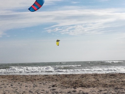 Zwei Kitesurfer gleiten über die Wellen am Strand.