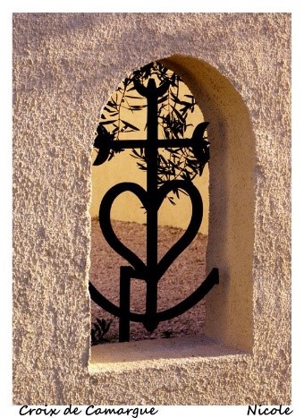Kunstvolle Metallkreuz- und Herzgestaltung in einer mauerartigen Nische.