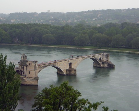 Brücke über einen Fluss mit grünen Bäumen im Hintergrund.