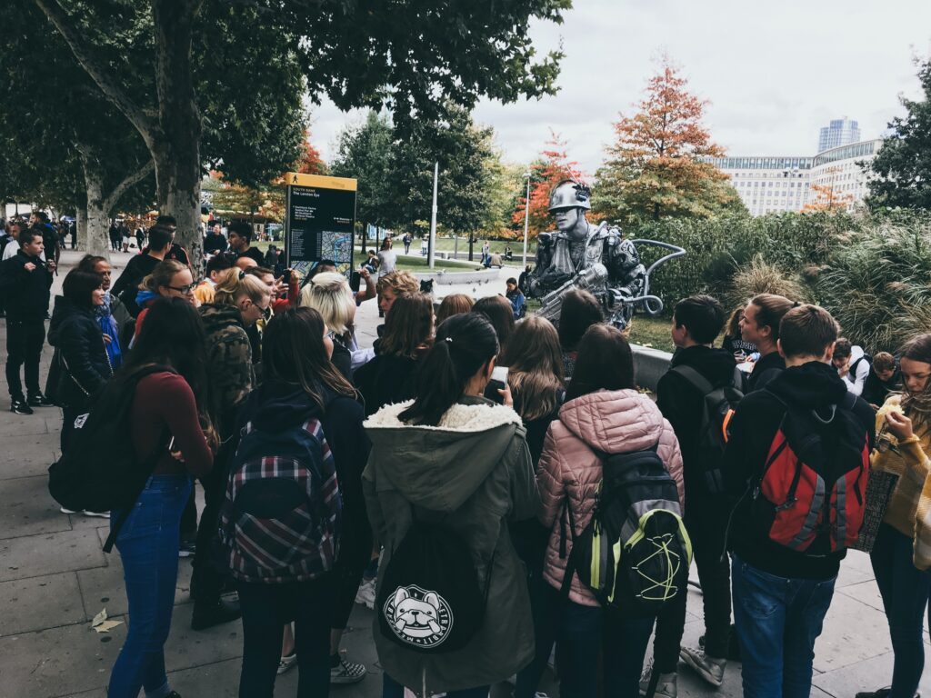 Gruppe von Schülern versammelt sich um einen Robotermenschen im Freien.