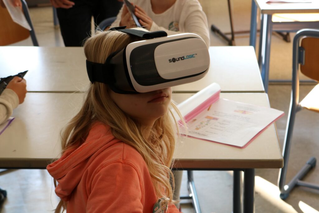 Schülerin mit VR-Brille im Klassenzimmer, schaut aufmerksam.