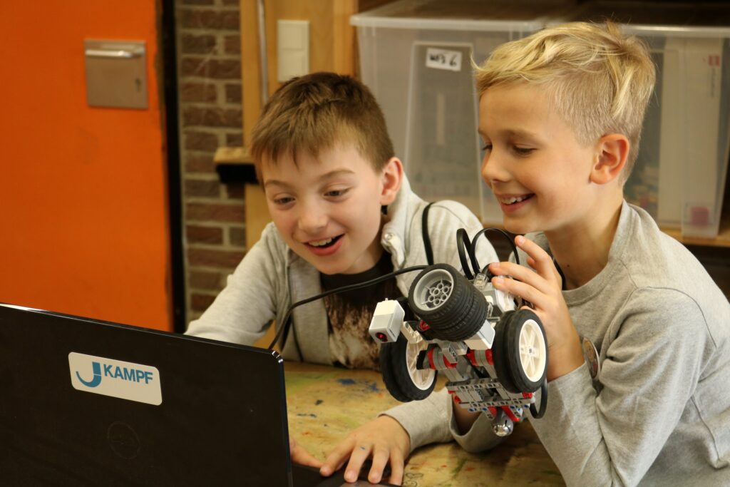 Zwei Jungen arbeiten begeistert an einem Computer mit einem Roboter.