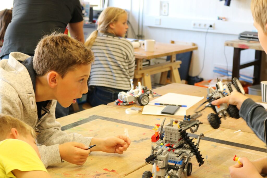 Kinder arbeiten an Robotermodellen in einem Klassenraum.