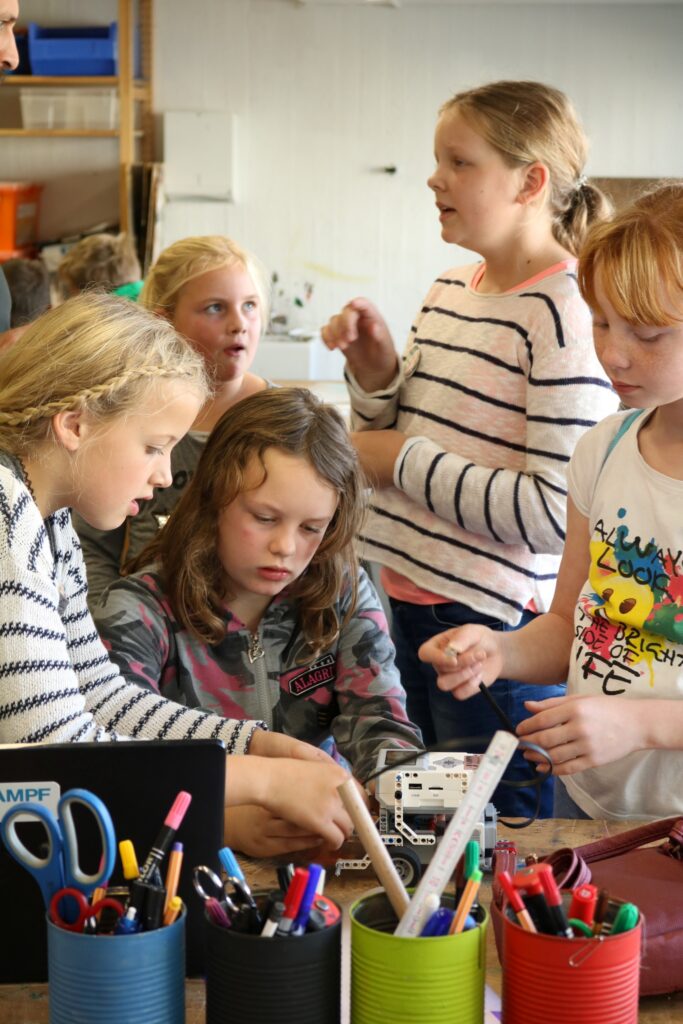 Sechs Kinder arbeiten gemeinsam an einem Projekt mit Stiften und Materialien.