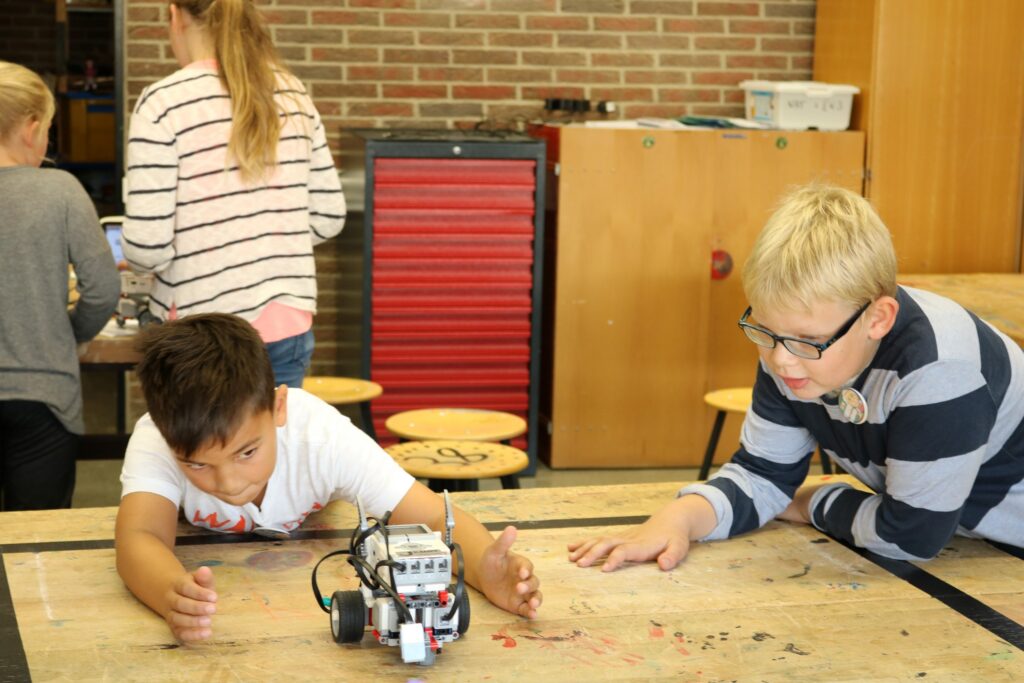 Kinder arbeiten an einem Tisch mit einem Roboter.