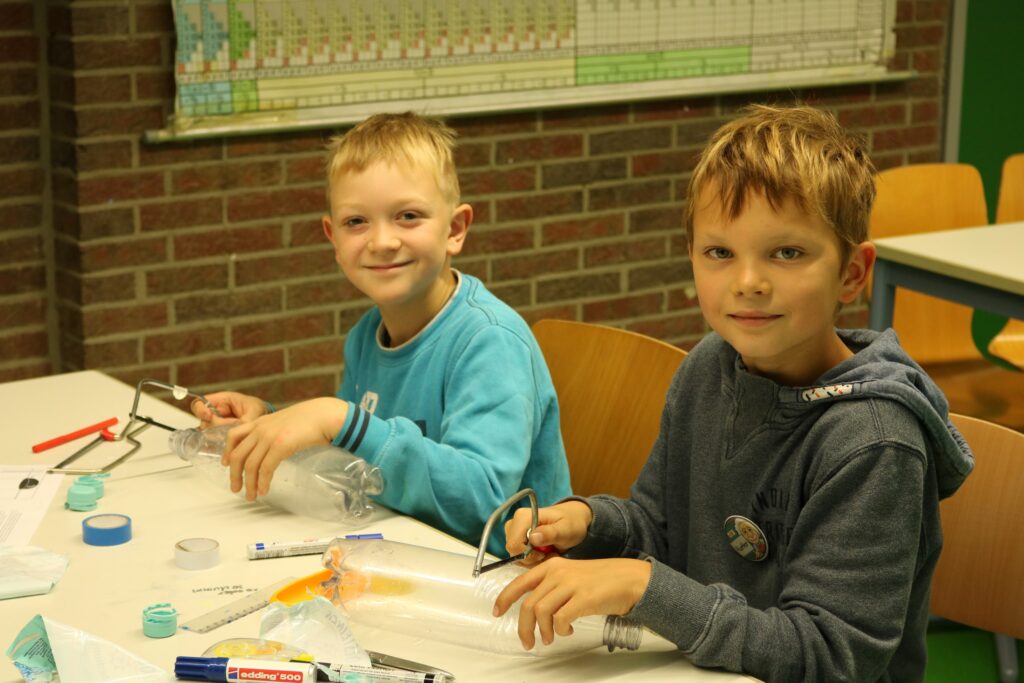 Zwei Jungen arbeiten an einem Bastelprojekt an einem Tisch.