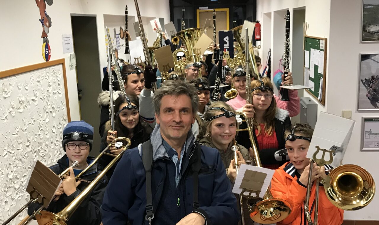 Schülerinnen und Schüler mit Musikinstrumenten in einer Schulflur.