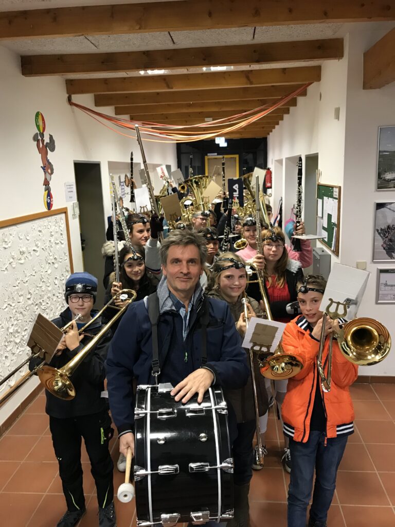 Schülerinnen und Schüler mit Musikinstrumenten in einer Schulflur.
