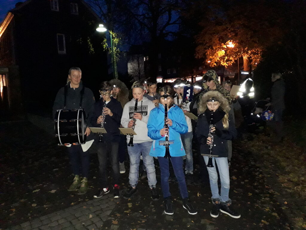 Musikgruppe mit Instrumenten steht im Freien bei Dämmerung.